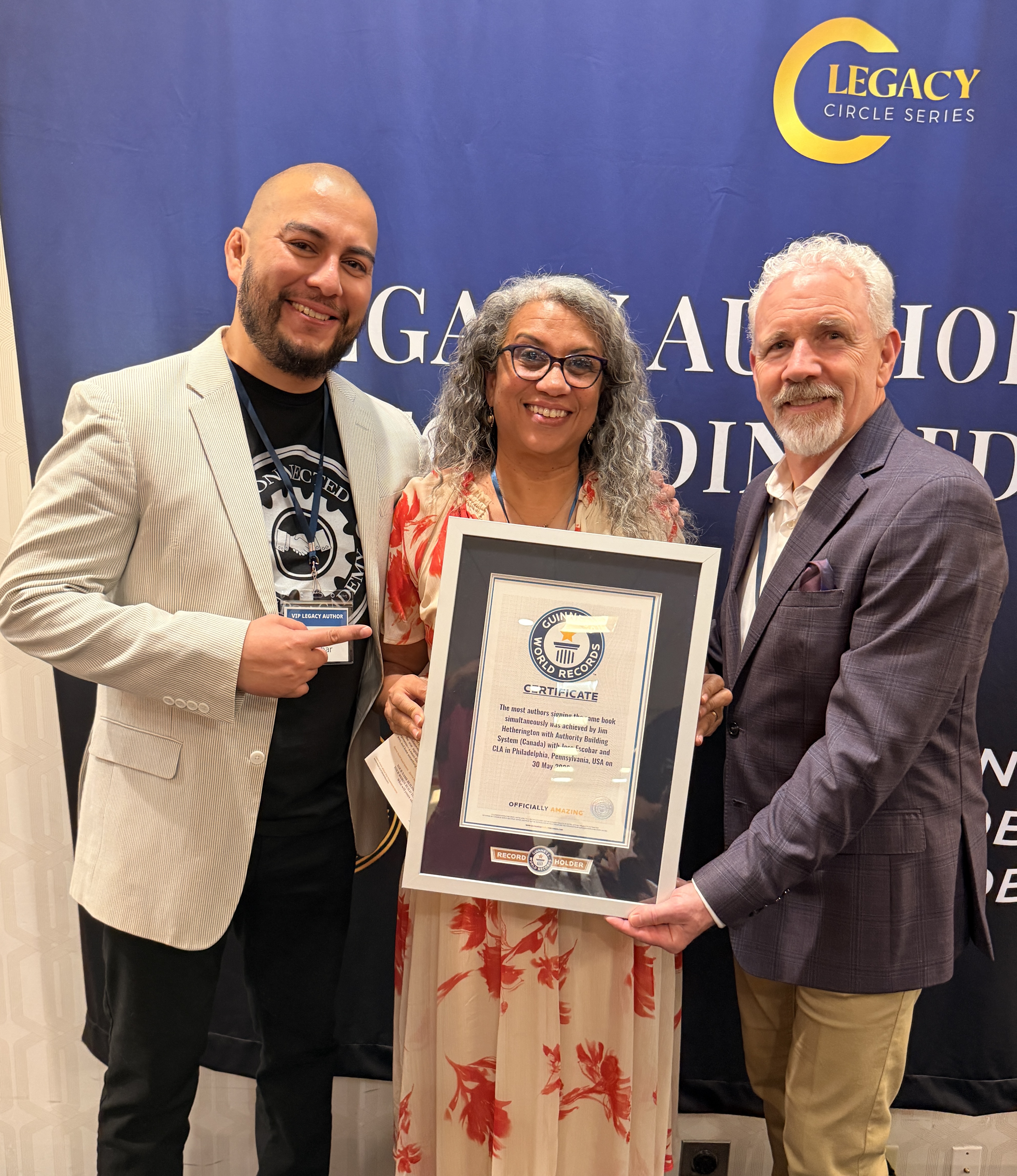 Leonne holding the Guinness World Record certificate with two colleagues at the Legacy Author Circle event in Philadelphia